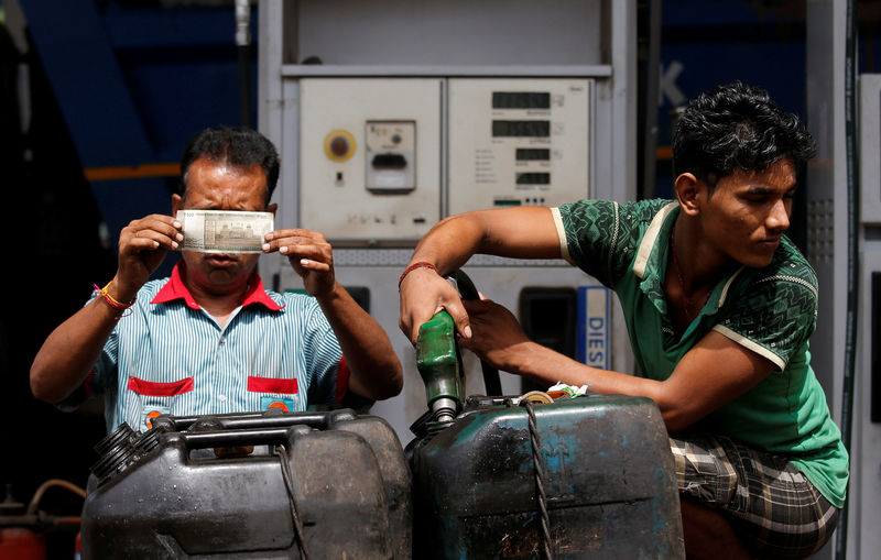 © Reuters. FILE PHOTO: A worker checks a 500 Indian rupee note as a man fills diesel in containers at a fuel station in Kolkata