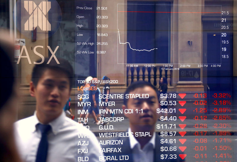© Reuters. Passanti davanti a un tabellone elettronico con le quotazioni dell'Australian Securities Exchange, la borsa di Sydney