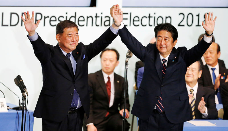 © Reuters. Japan's PM Abe, who is also the ruling LDP leader, raises his hands with former defence minister Ishiba after Abe won the ruling party leadership vote at the party's headquarters in Tokyo