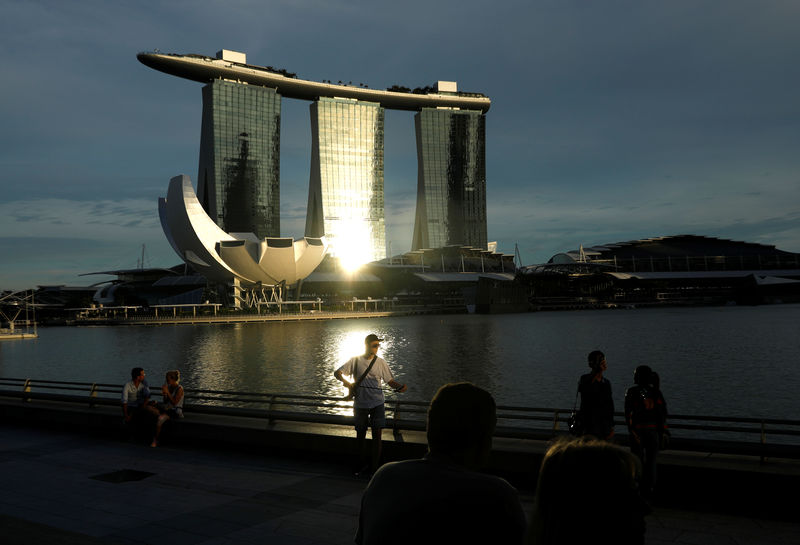 © Reuters. FILE PHOTO: People sit along Marina Bay in Singapore