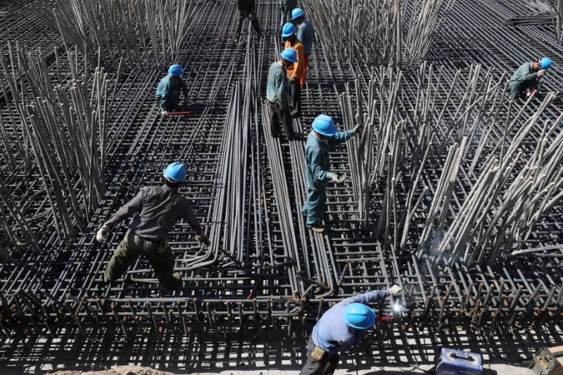 © Reuters. Workers are seen amid steel bars at a construction site of a highway in Zhaotong