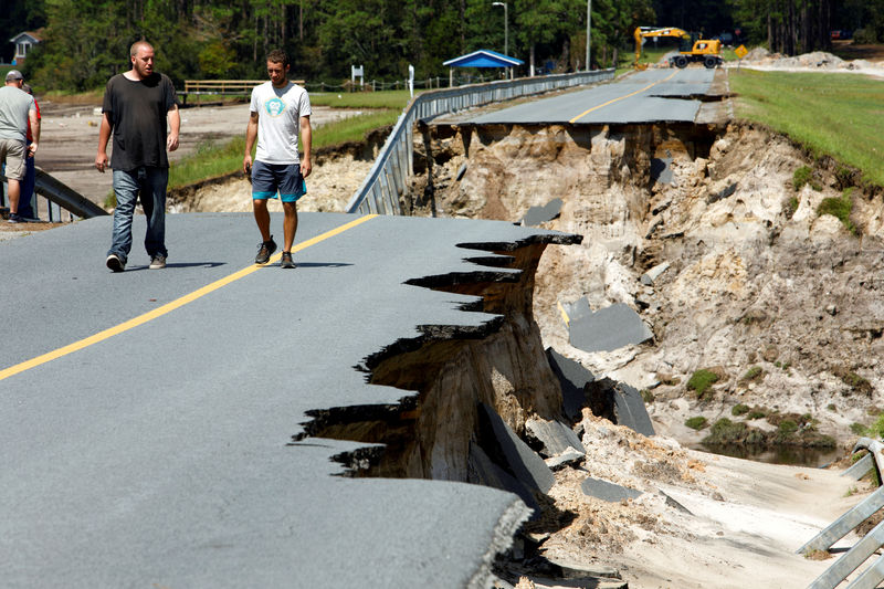 © Reuters. Moradores caminham em estrada destruída por furacão Florence na Carolina do Norte