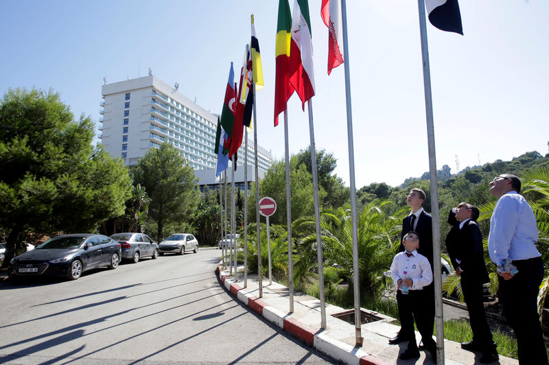 © Reuters. People look at flags ahead of  the OPEC Ministerial Monitoring Committee in Algiers