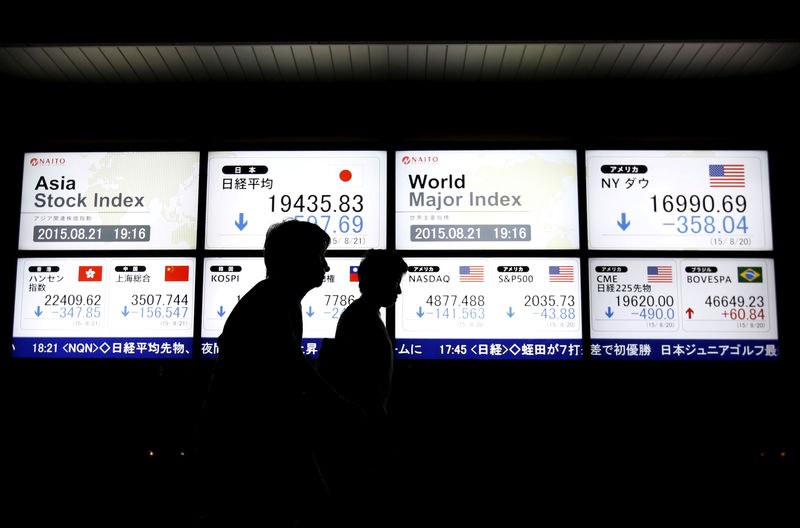 © Reuters. Imagen de archivo de dos personas caminando frente a pantallas que muestran varios índices bursátiles en Tokio