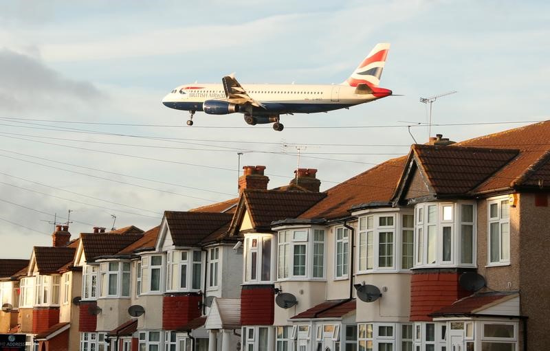 © Reuters. A British Airways Airbus A320 passes over homes in Myrtle Avenue as it comes into land at Heathrow Airport, London