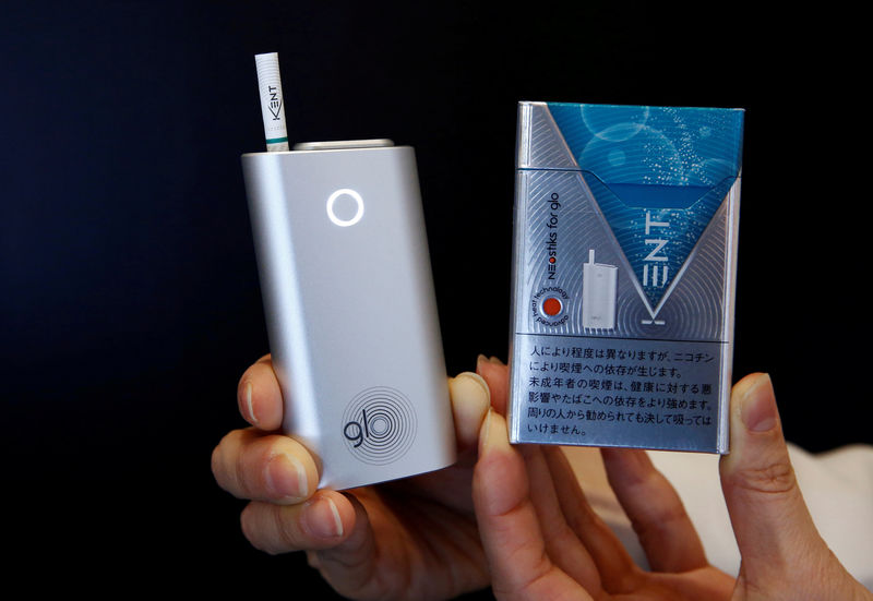 © Reuters. FILE PHOTO: A promoter shows British American Tobacco's new tobacco heating system device 'glo' (L) and Kent tobacco after a news conference in Tokyo, Japan