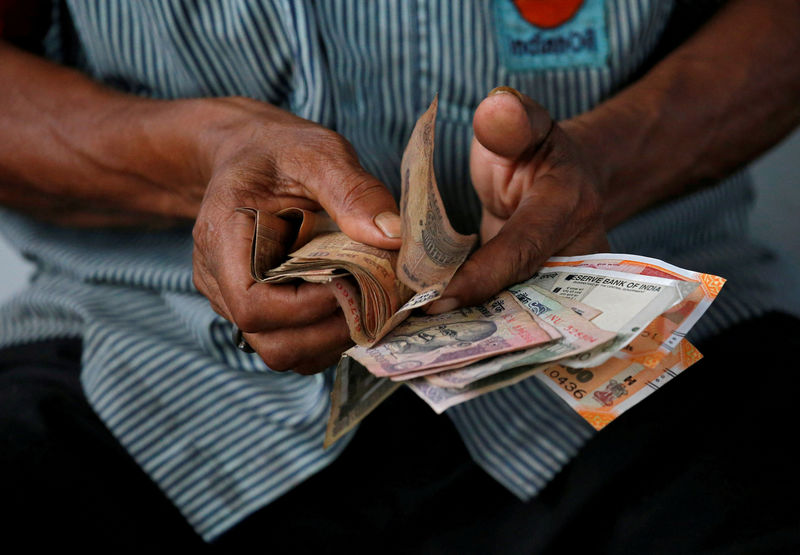 © Reuters. FILE PHOTO: An attendant at a fuel station arranges Indian rupee notes in Kolkata