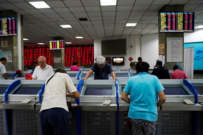 © Reuters. FILE PHOTO: Investors look at computer screens showing stock information at a brokerage house in Shanghai