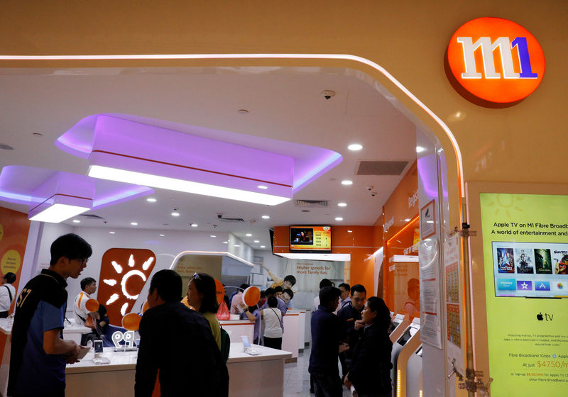 © Reuters. FILE PHOTO: People shop for handsets at an M1 mobile shop in Singapore