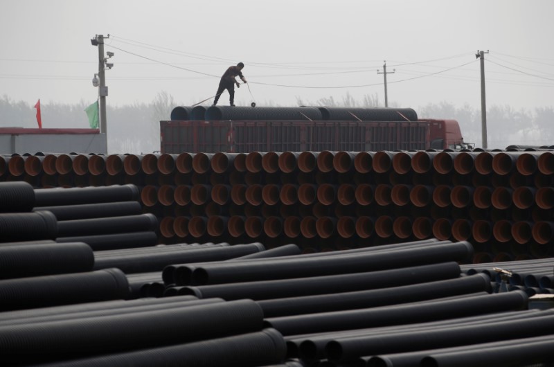 © Reuters. A worker packs pipelines onto a truck at a local plastic pipe factory in Donghegang village on the outskirts of Xiongxian county