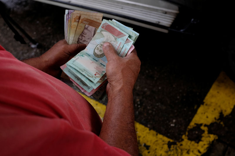 © Reuters. Un trabajador de una gasolinera de PDVSA cuenta bolívares en Caracas