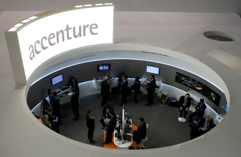 © Reuters. FILE PHOTO - Visitors look at devices at Accenture stand at the Mobile World Congress in Barcelona