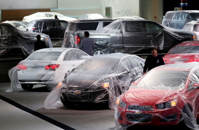 © Reuters. FILE PHOTO: Vehicles are covered with protective wrap as workers prepare the General Motors automakers display  in Detroit