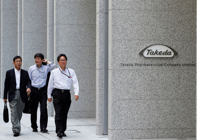 © Reuters. People walk past the new headquarters of Takeda Pharmaceutical Co in Tokyo