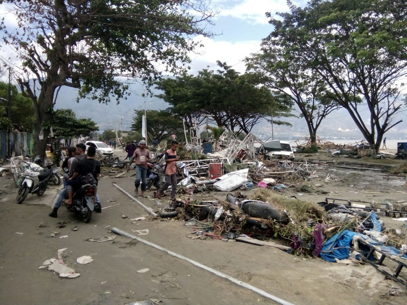 © Reuters. Resident checks dead bodies to find their family at a street after tsunami hit in Palu