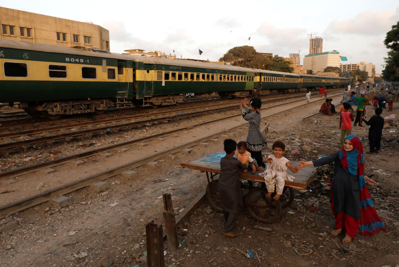 © Reuters. Children play as a passenger train passes along a neighbourhood in Karachi