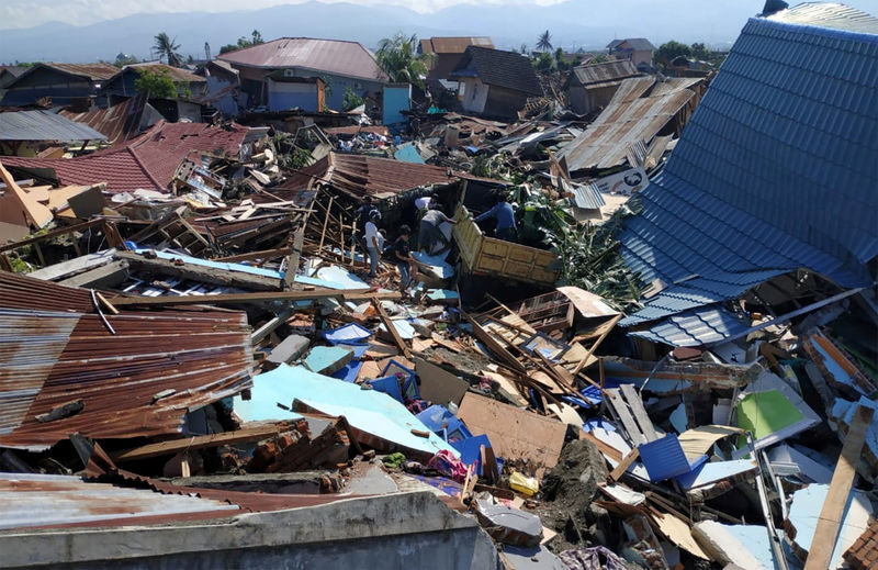 © Reuters. People search through debris in a residential area following an earthquake and tsunami in Palu