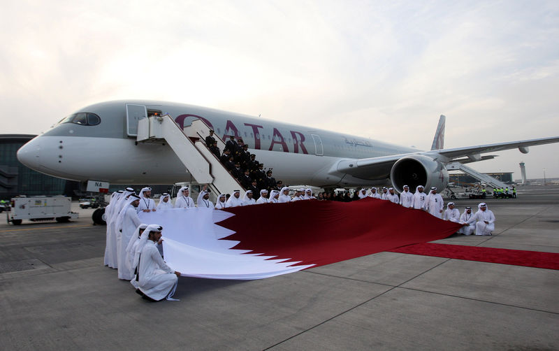 © Reuters. FILE PHOTO: Qatar Airways staff hold a Qatari flag in front of an Airbus A350-1000 at Hamad International Airport in Doha