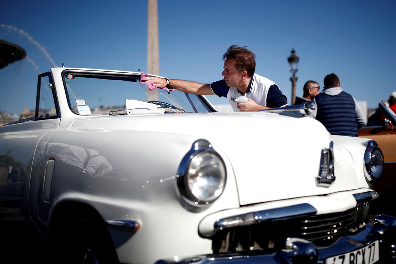 © Reuters. FILE PHOTO: A car enthusiast cleans the windshield of his Studebaker cabriolet during a parade on the Place de la Concorde organized as part of the Paris auto show, which is celebrating its 120th edition, in Paris