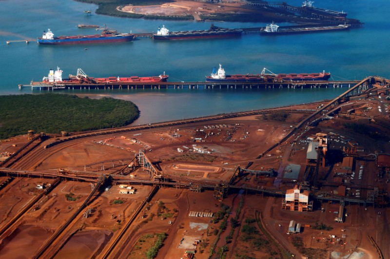 © Reuters. FILE PHOTO:  File picture of ships waiting to be loaded near piles of iron ore and bucket-wheel reclaimers at the Fortescue loading dock located at Port Hedland