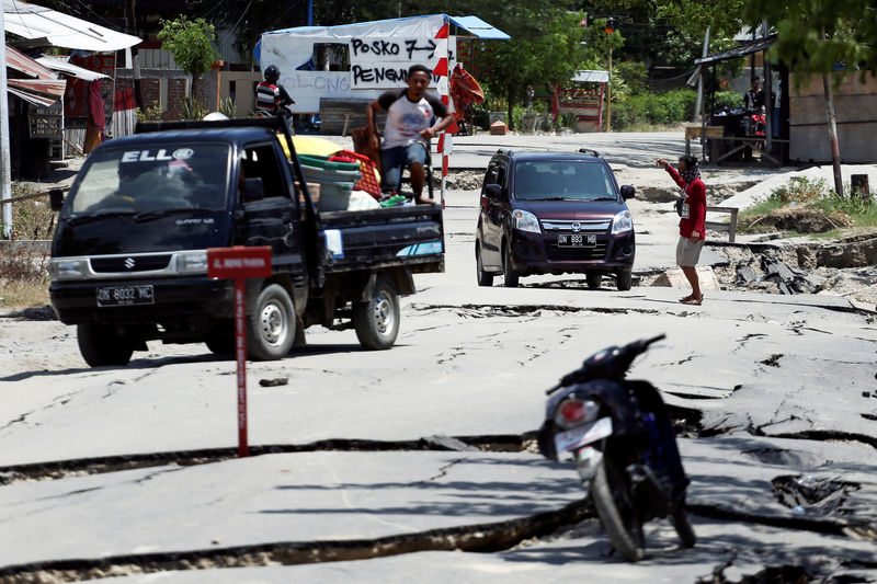 © Reuters. Cars pass a damaged section of a road following the earthquake in Palu, Central Sulawesi