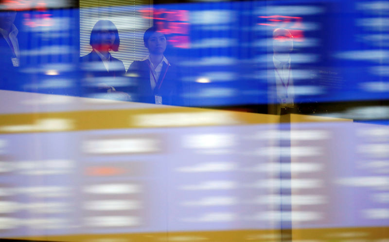 © Reuters. Visitors are seen as market prices are reflected in a glass window at the TSE in Tokyo