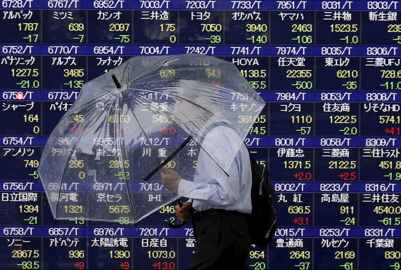 © Reuters. Прохожий у электронного табло с котировками акций возле брокерской фирмы в Токио