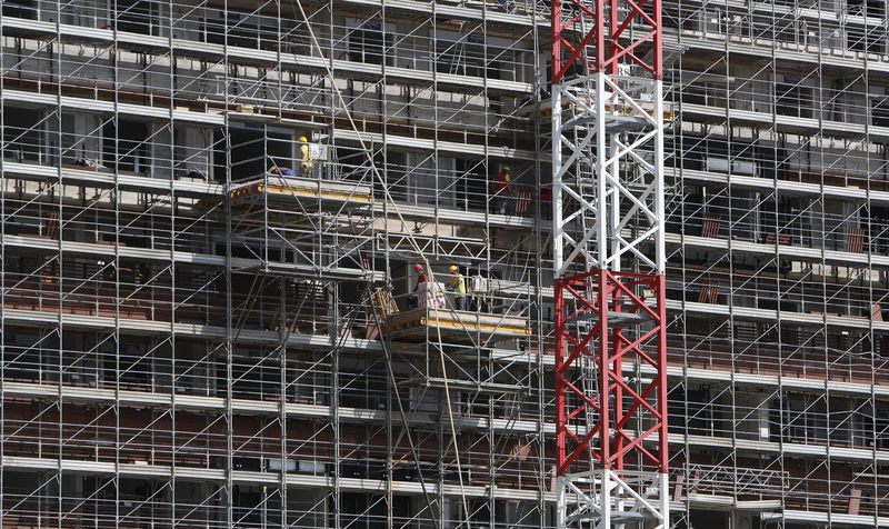 © Reuters. FILE PHOTO:  Labourers work at the scaffolding of a building in downtown Milan