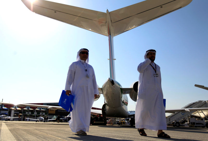 © Reuters. FILE PHOTO: Visitors walk past aircraft on display during the Middle East Business Aviation show at Al Maktoum International Airport