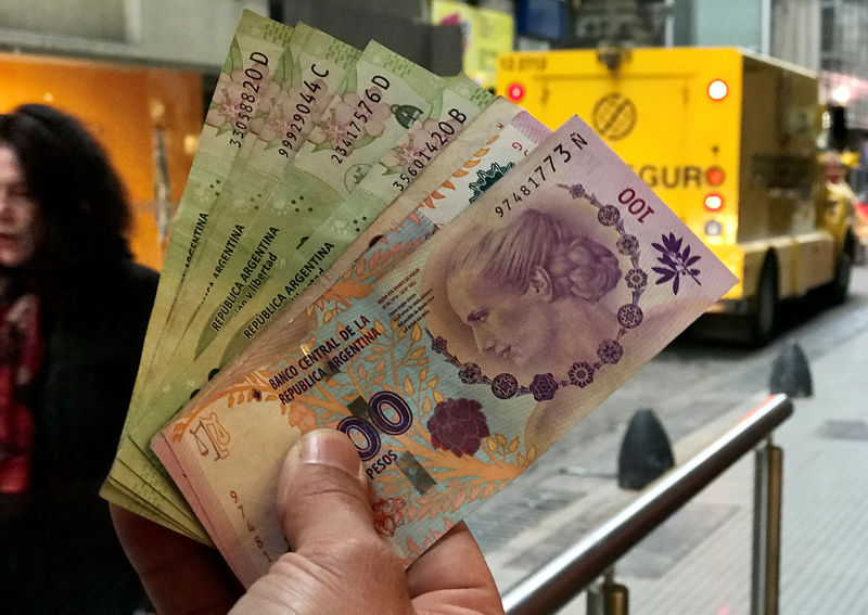 © Reuters. A man shows Argentine pesos outside a bank in Buenos Aires' financial district