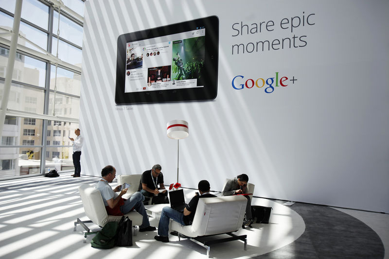 © Reuters. Pessoas sentadas em frente a anúncio do Google+ durante evento da empresa em São Francisco, Estados Unidos