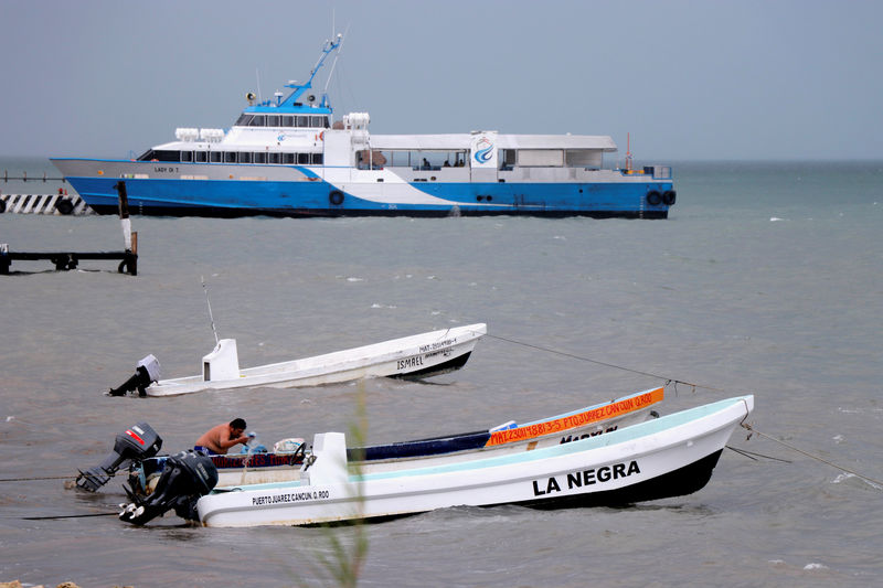 © Reuters. Homem empurra barco enquanto tempestade tropical Michael se aproxima de Cancún, no México