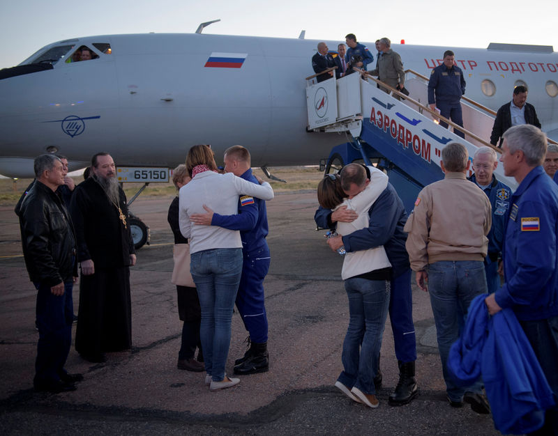 © Reuters. Cosmonauta russo Alexey Ovchinin e astronauta dos EUA Nick Hague abraçam familares após pouso de emergência no Cazaquistão