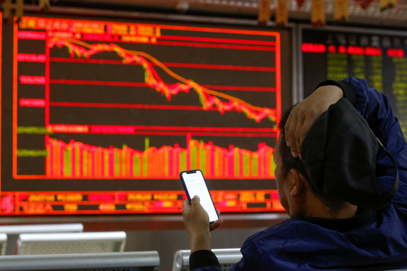 © Reuters. An investor sits in front of displays showing stock information at a brokerage office in Beijing