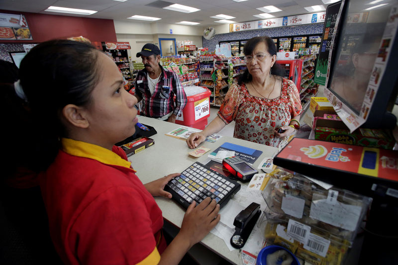 © Reuters. An employee of Femsa's Oxxo convenience store serves customers at a store in Monterrey