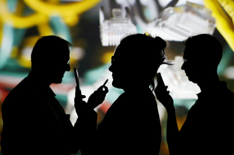 © Reuters. FOTO DE ARCHIVO: Un grupo de personas mira sus móviles con un fondo de cabes de internet