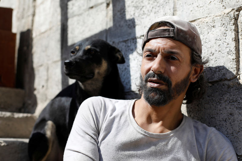 © Reuters. Abu Nimr, 36, is pictured with his dog in Yarmouk Palestinian camp in Damascus