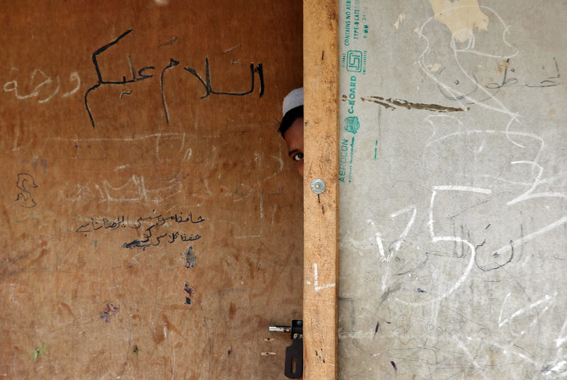 © Reuters. Un joven de la comunidad rohinyá se asoma por una puerta de una madrasa, una escuela religiosa, en un campamento en las afueras de Jammu