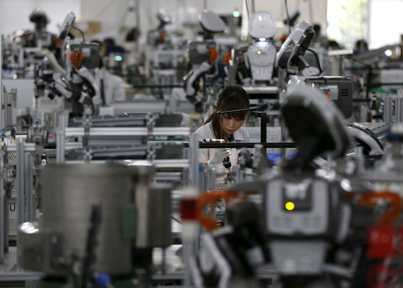 © Reuters. FILE PHOTO: A humanoid robot works side by side with employees in the assembly line at a factory of Glory Ltd., a manufacturer of automatic change dispensers, in Kazo, north of Tokyo
