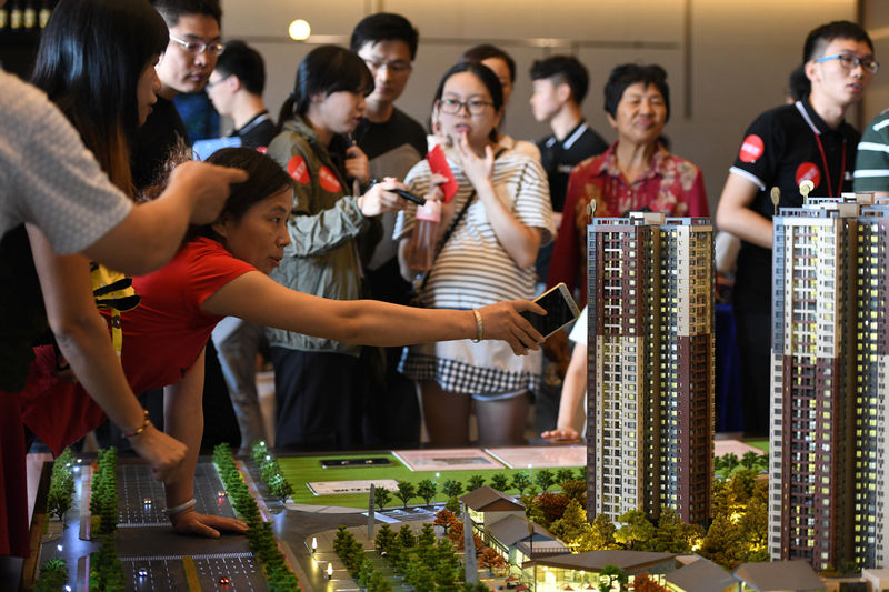 © Reuters. Woman points at the model of a residential compound by China Vanke as a sales agent introduces the property to the visitors at its showroom in Dongguan