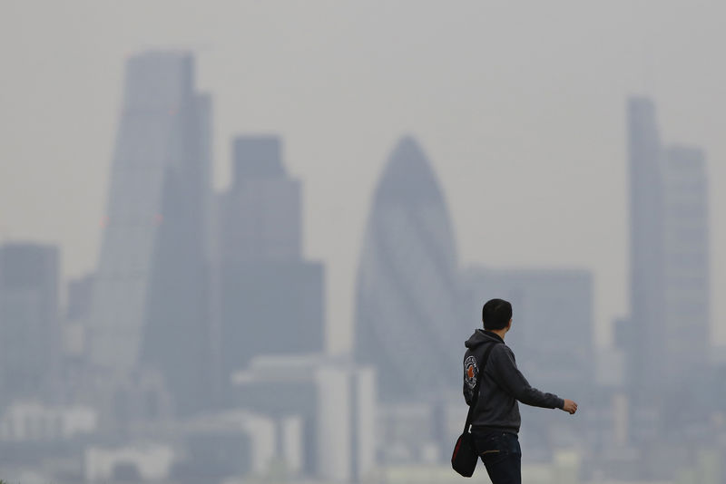 © Reuters. A man walks through Greenwich Park as a haze of pollution sits over the London skyline