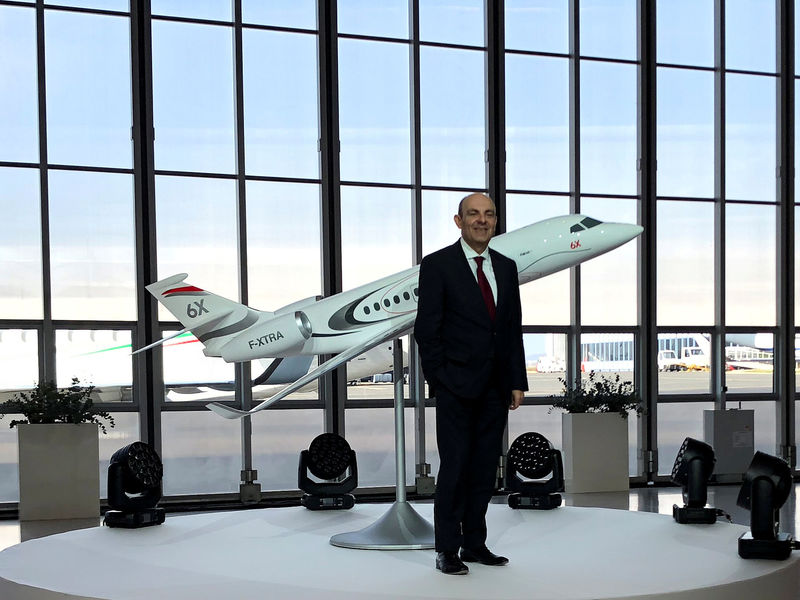 © Reuters. FILE PHOTO: Dassault Aviation CEO Eric Trappier poses in a hangar in front of a model of the Falcon 6X, a new business jet due to enter service in 2022, in Le Bourget