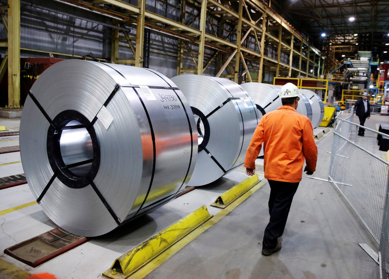 © Reuters. FILE PHOTO: A worker walks by rolled up steel sits in the ArcelorMittal Dofasco steel plant in Hamilton, Ontario