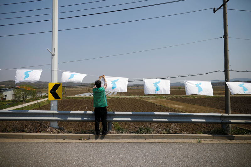 © Reuters. A man hangs a unification flag on the Grand Unification Bridge which leads to the Peace House in Paju