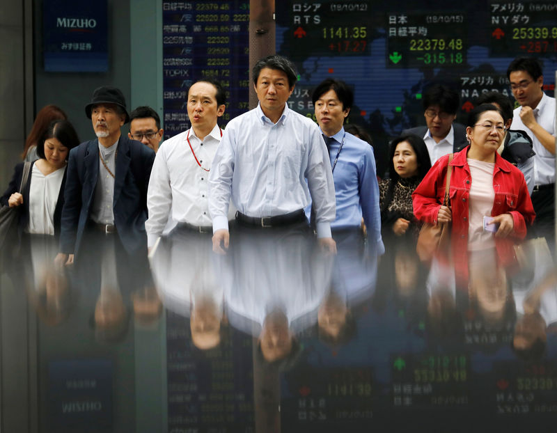 © Reuters. People walk in front of an electronic stock quotation board outside a brokerage in Tokyo