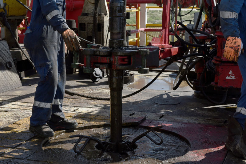 © Reuters. FILE PHOTO: A drilling crew uses a mechanical roughneck machine to thread drill pipe together on an oil rig in the Permian Basin near Wink
