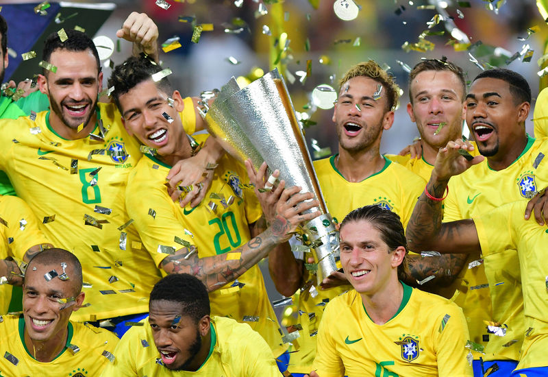 © Reuters. Neymar, Roberto Firmino y sus compañeros de equipo celebran con un trofeo su victoria frente a Argentina, en Yeda, Arabia Saudita.