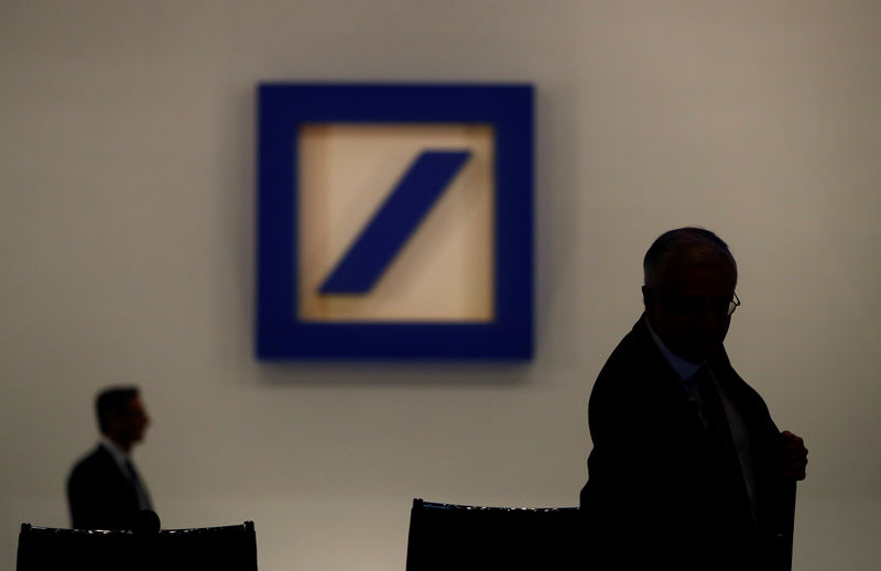 © Reuters. People are silhouetted next to the Deutsche Bank's logo prior to the bank's annual meeting in Frankfurt