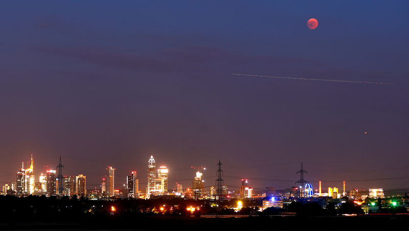 © Reuters. A blood moon is seen in the sky over the skyline of Frankfurt as an airplane passes by