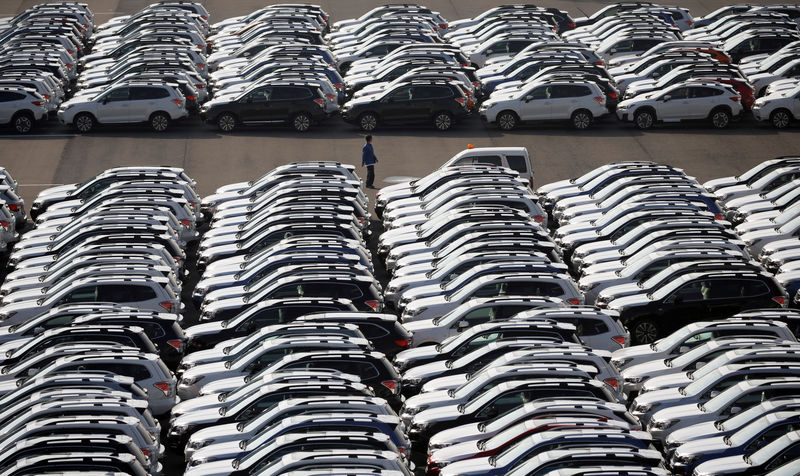 © Reuters. A worker is seen among newly manufactured cars awaiting export at port in Yokohama